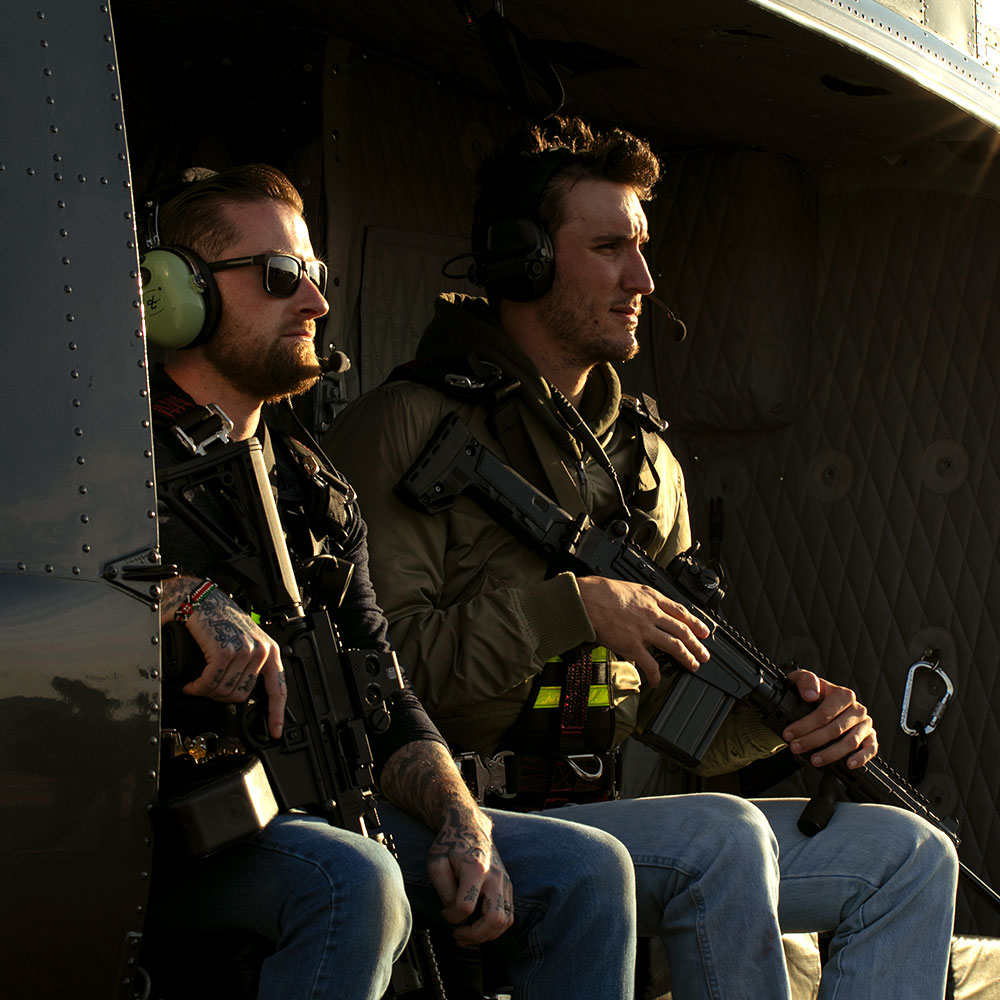 Two men sitting in the helicopter with machine guns