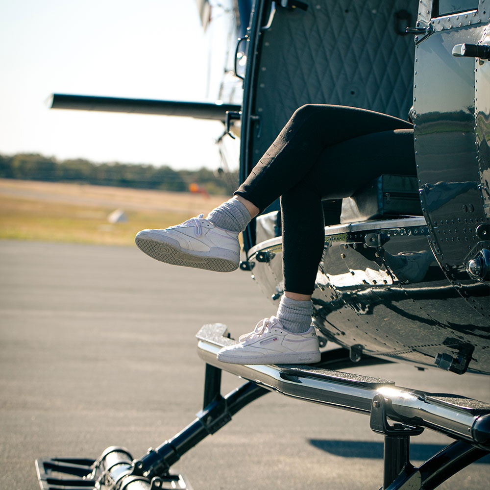 A girl's legs hanging out of a helicopter